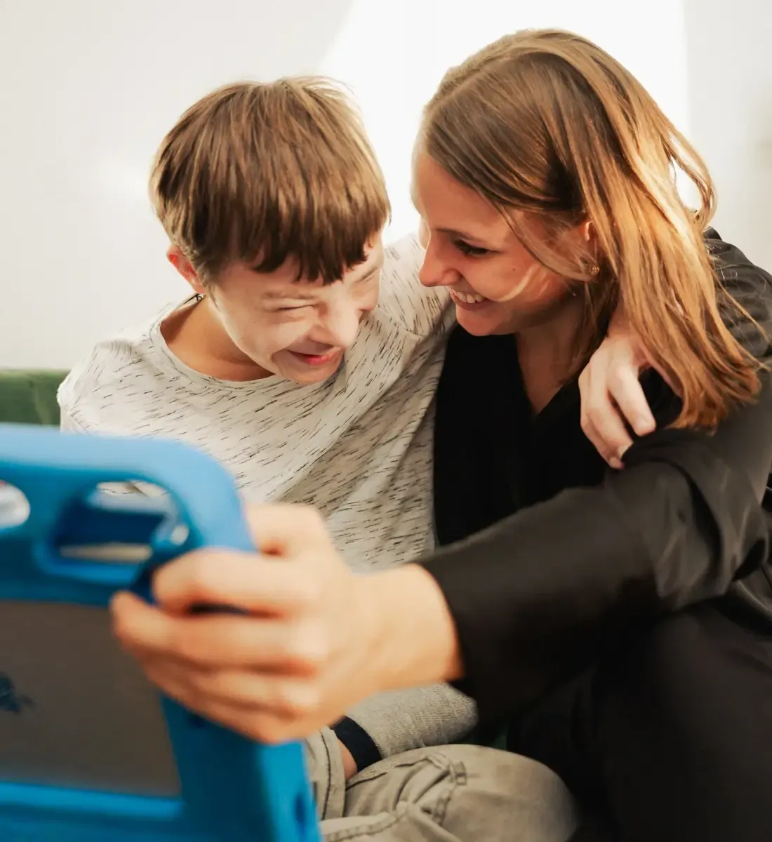 Julia und Alex lachen zusammen, während sie sich auf seinem Talker ein vergangenes Ereignis ansehen.